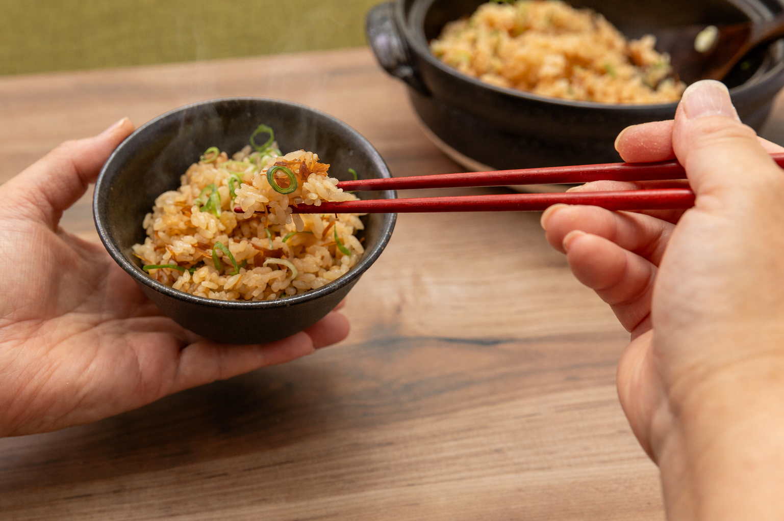 ねぎを添えたほたて釜飯を茶碗で味わう様子