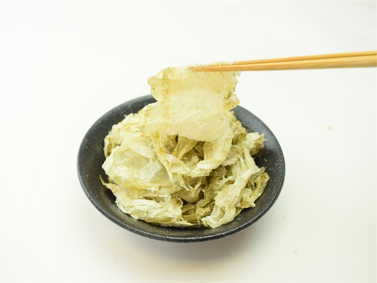 箸で持ち上げた透き通るほど薄い黒おぼろ昆布